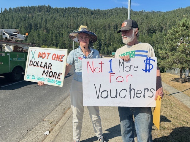 Protesters outside the "Capital for a Day" event in Orofino on July 24 hold signs with the slogan "Not One Dollar More" to show displeasure with the school voucher bill Gov. Little signed.